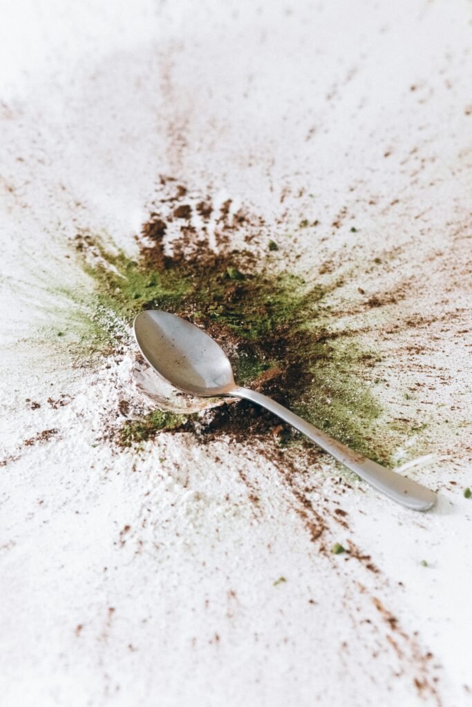A spoon surrounded by a colorful burst of spices on a white background, creating an abstract splash.